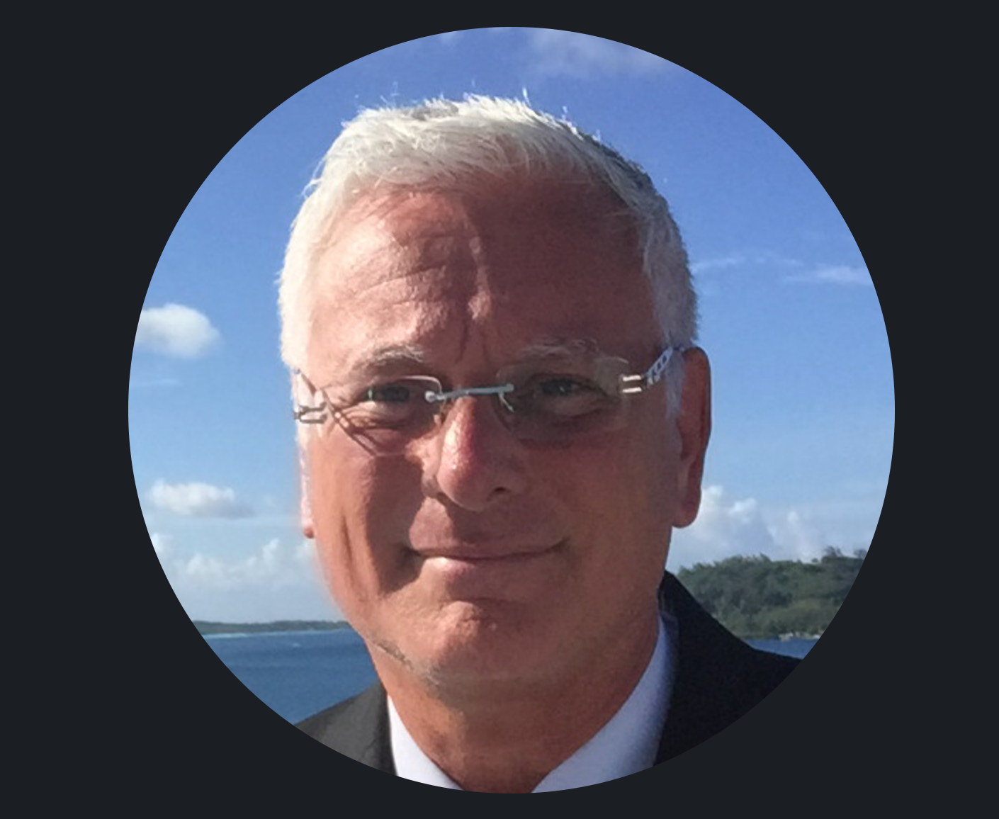 John Ekin smiling outdoors beside the sea